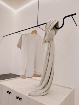 Elegant display of minimalist silk scarves in soft beige and cream tones, gently folded on a wooden surface.
