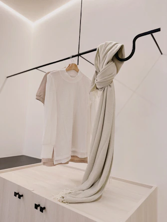 Minimalist display of silk scarves in neutral tones elegantly draped over a white chair.