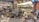 A colorful souvenir shop filled with various items including textiles, ceramics, clothing, hats, and bags. The shelves are densely packed with products like postcards, magnets, and other decorative pieces. Bright lighting highlights the vibrant assortment of items.