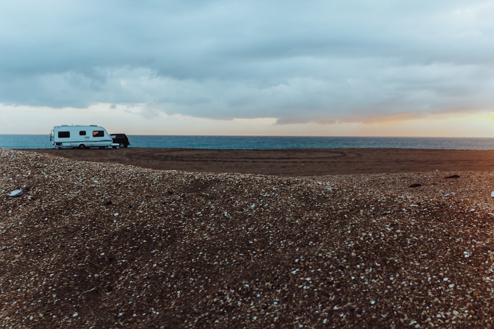 um caminhão branco dirigindo por uma estrada de terra ao lado do oceano