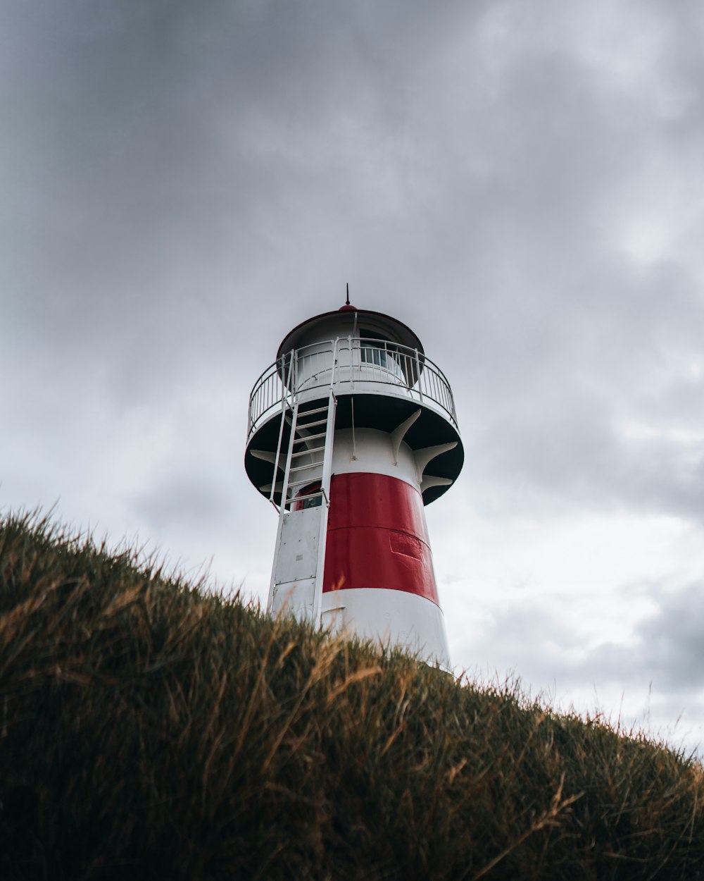 a red and white lighthouse on top of a hill