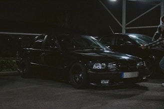 A close-up photo of a suspicious figure lurking near a parked car at dusk.