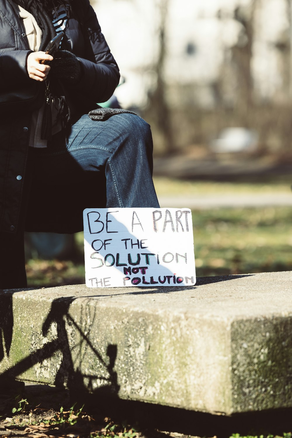 a person sitting on a bench with a sign