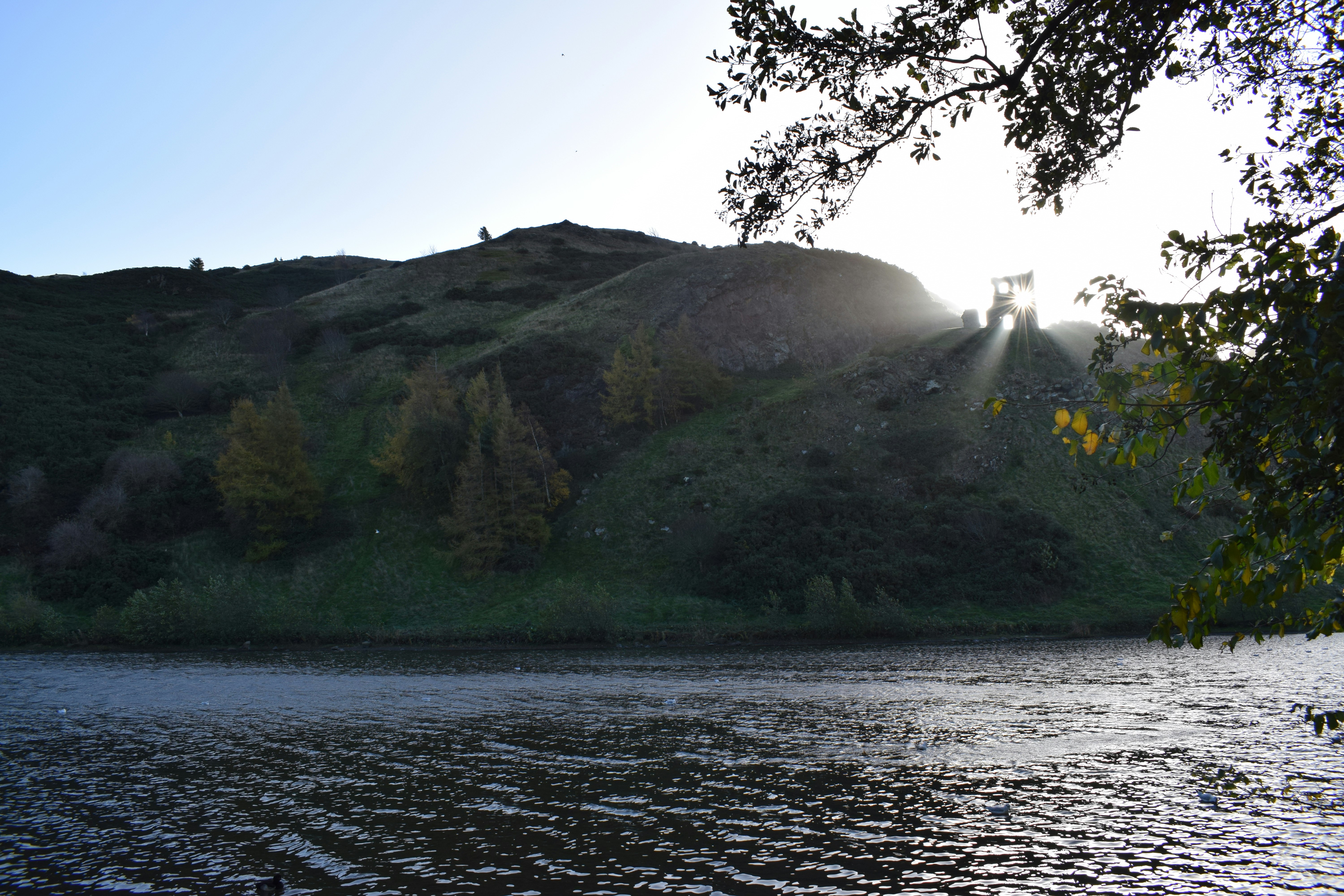 a body of water with a hill in the background, 