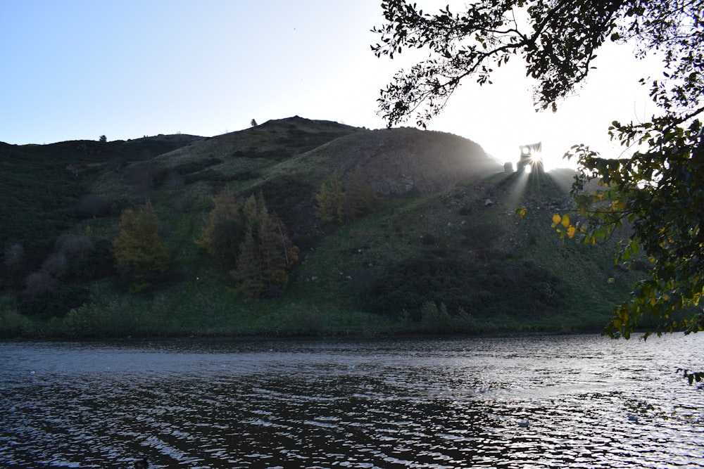 a body of water with a hill in the background