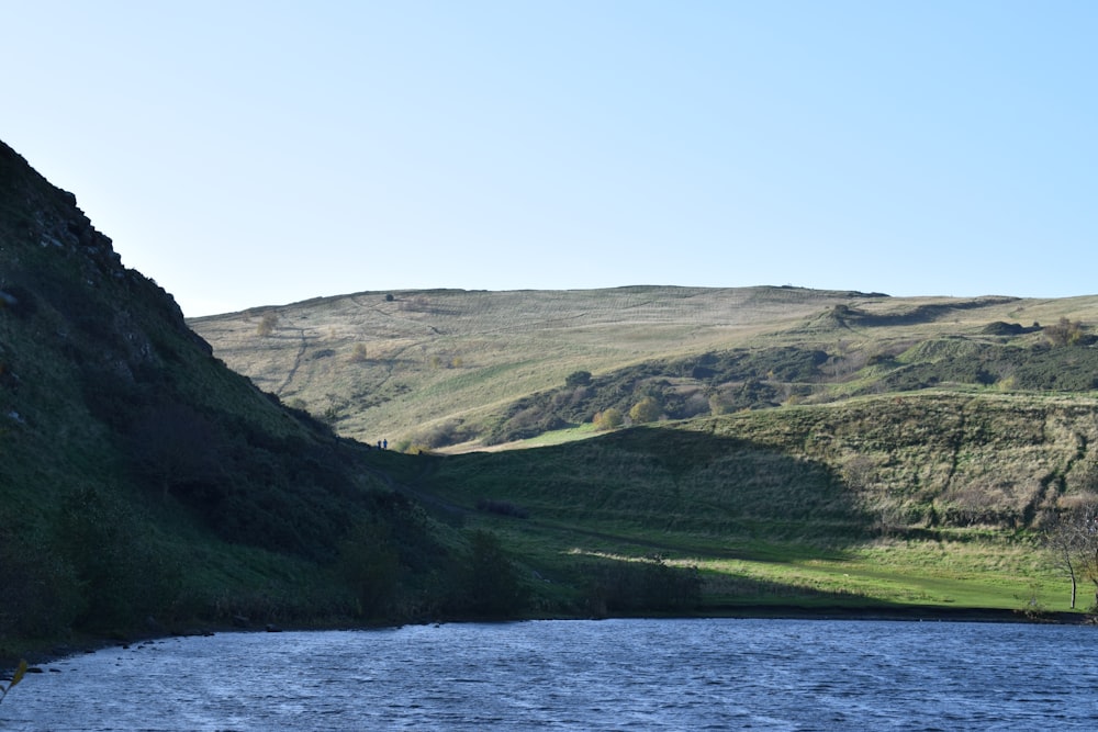 a body of water surrounded by a lush green hillside