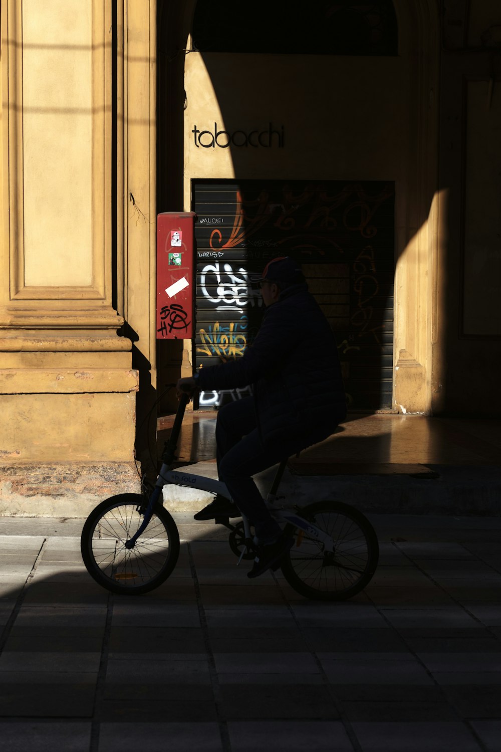 a man riding a bike down a street next to a tall building