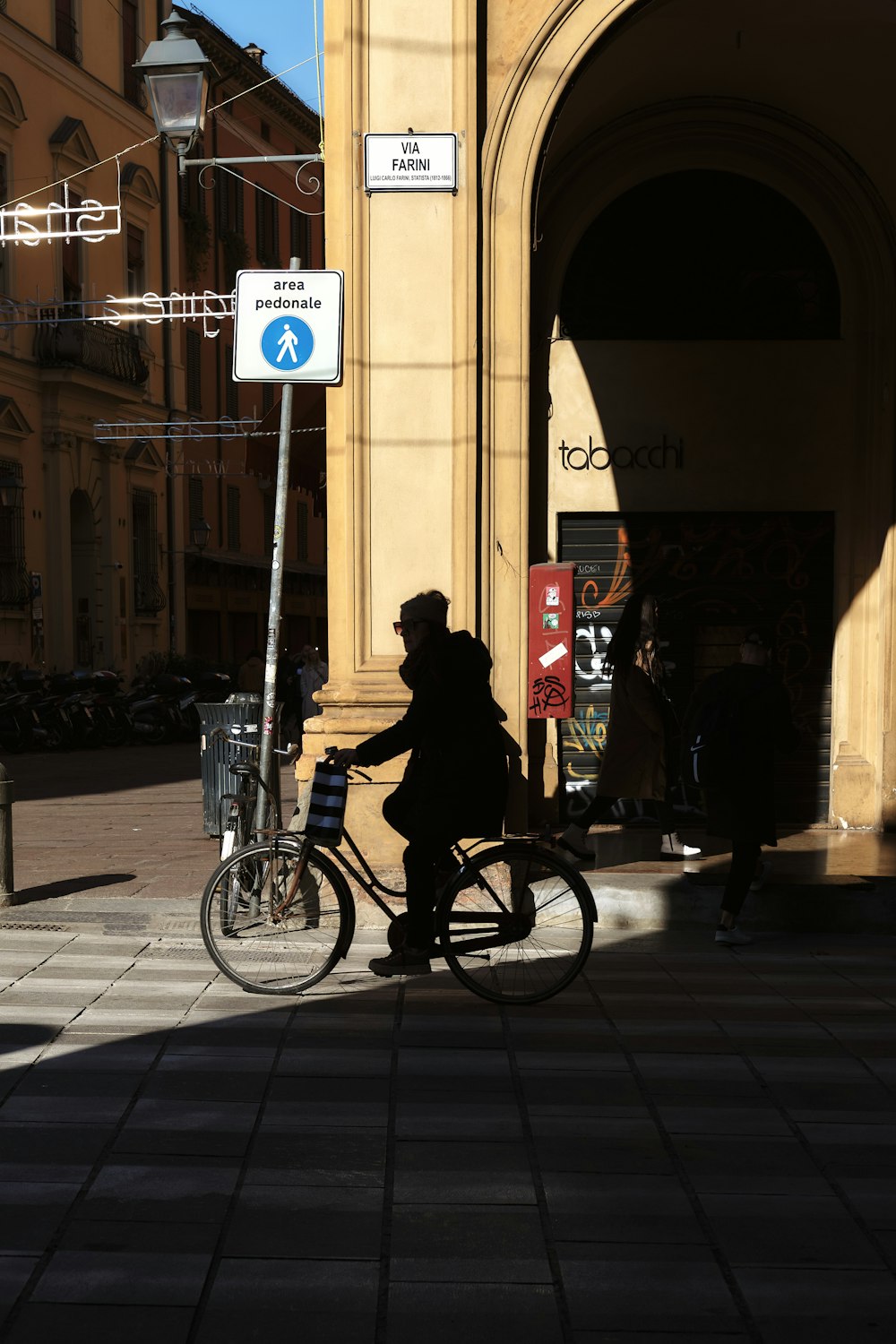 a man riding a bike down a street next to a tall building