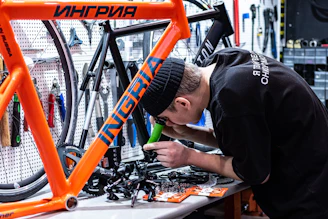 Craftsman carefully assembling a custom bicycle frame in a bright workshop.