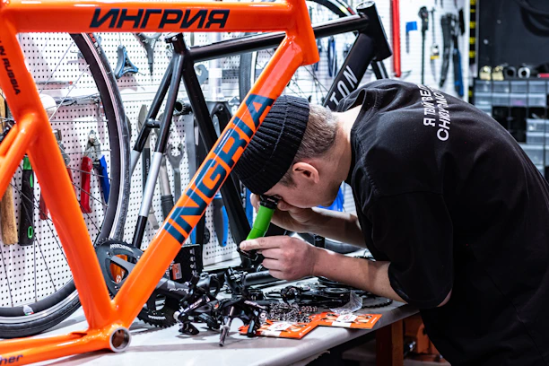 A skilled technician carefully assembling a sleek bicycle in a bright workshop.