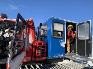 A professional driver opening the door of a high-end vehicle for passengers at a ski resort.