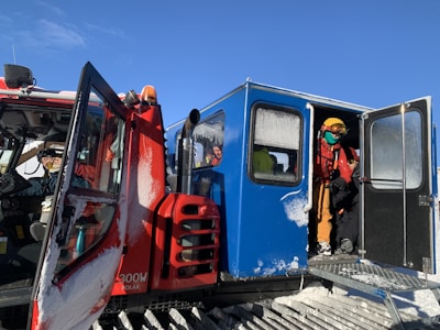 A professional driver opening the door of a high-end vehicle for passengers at a ski resort.