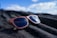 A stylish pair of sunglasses resting on a wooden table with a beach background.