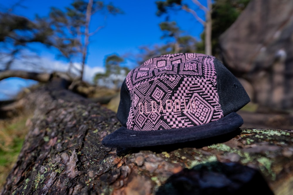 a pink and black hat sitting on top of a tree branch