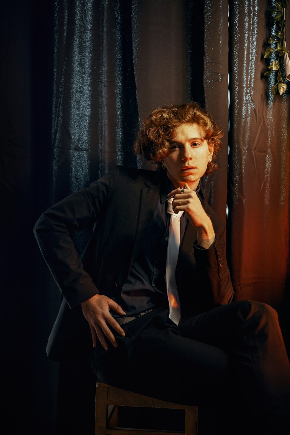 a man sitting on a stool wearing a suit and tie