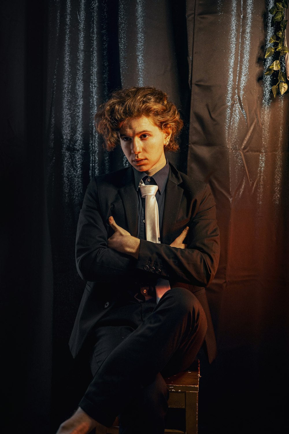 a man in a suit and tie sitting on a stool