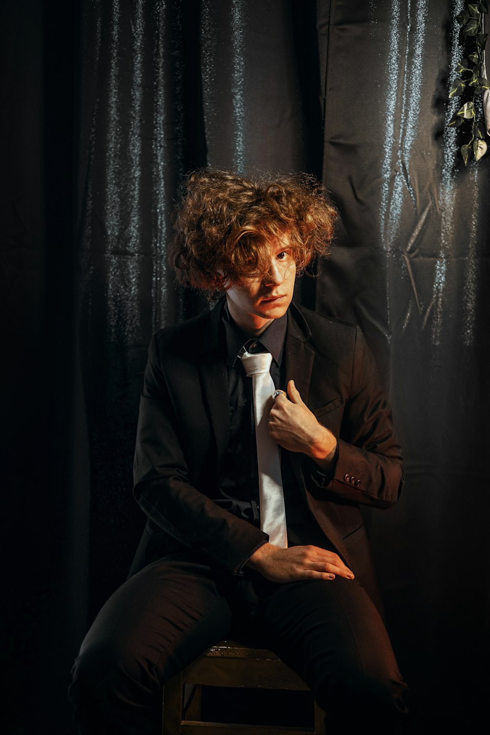 a man in a suit and tie sitting on a stool