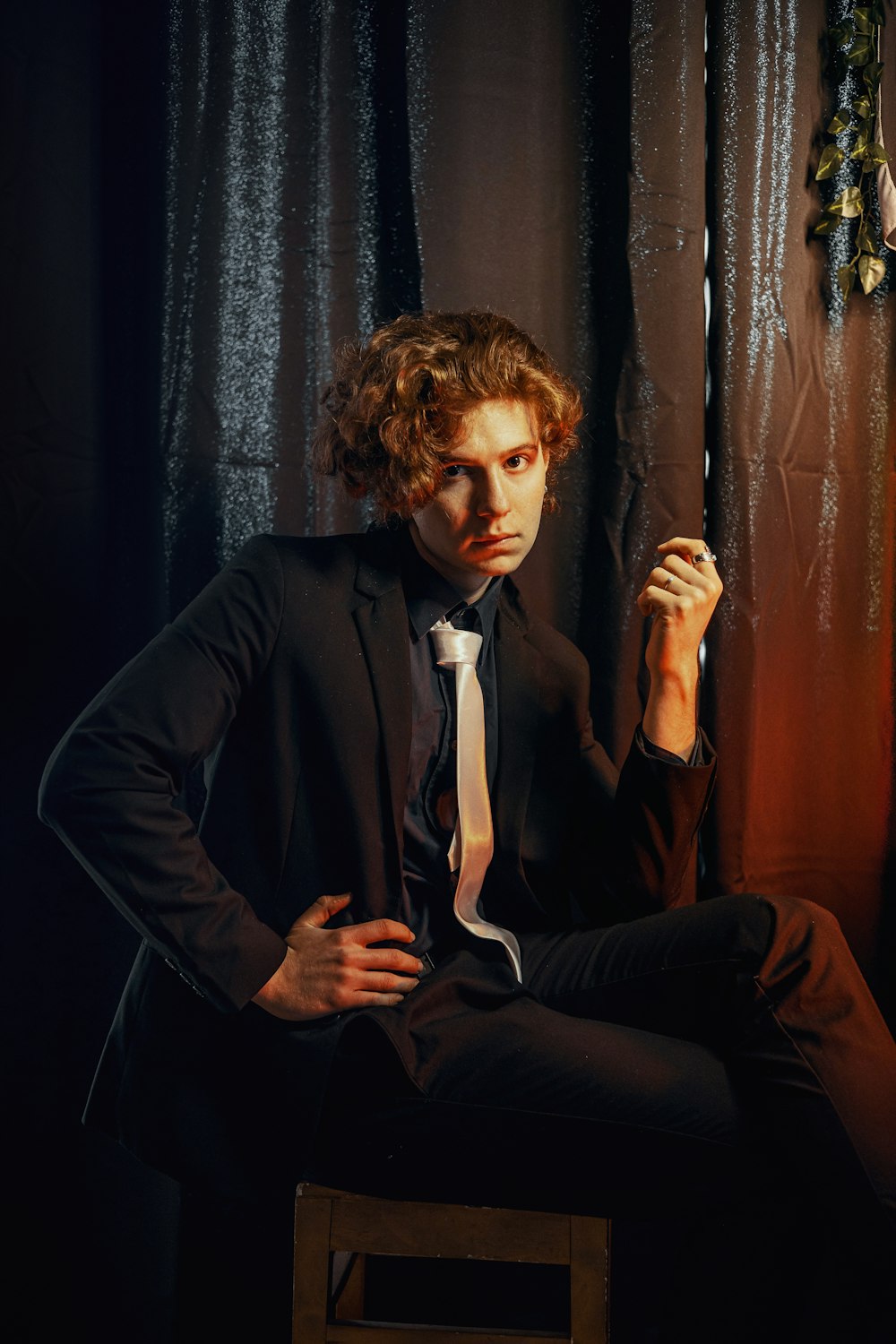 a man in a suit and tie sitting on a stool