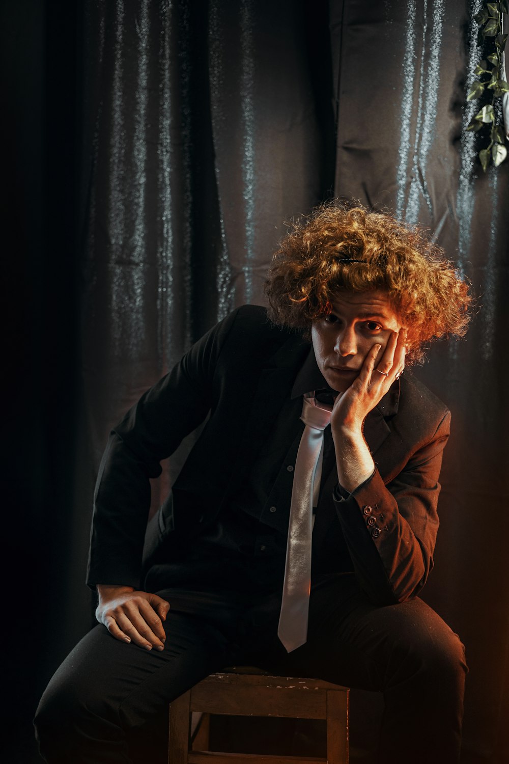 a man in a suit and tie sitting on a stool