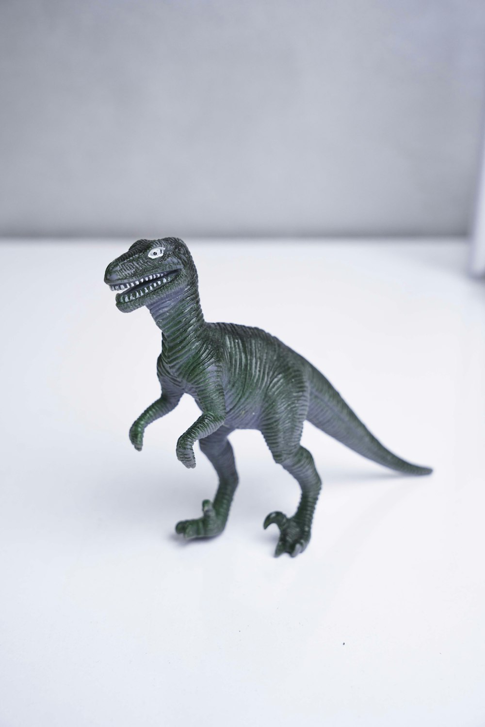 a toy dinosaur is standing on a white surface