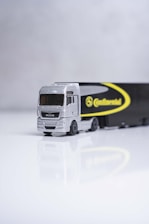 a toy truck with a trailer on a white surface