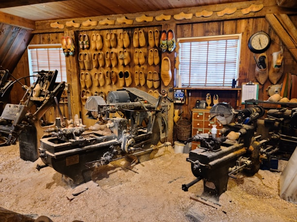 A cozy workshop with wooden shoe racks in various stages of craftsmanship, sunlight streaming through a window.