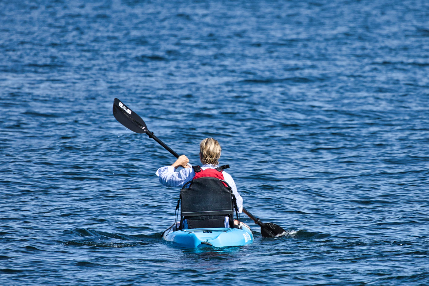 Paddler seated in a kayak on open blue water