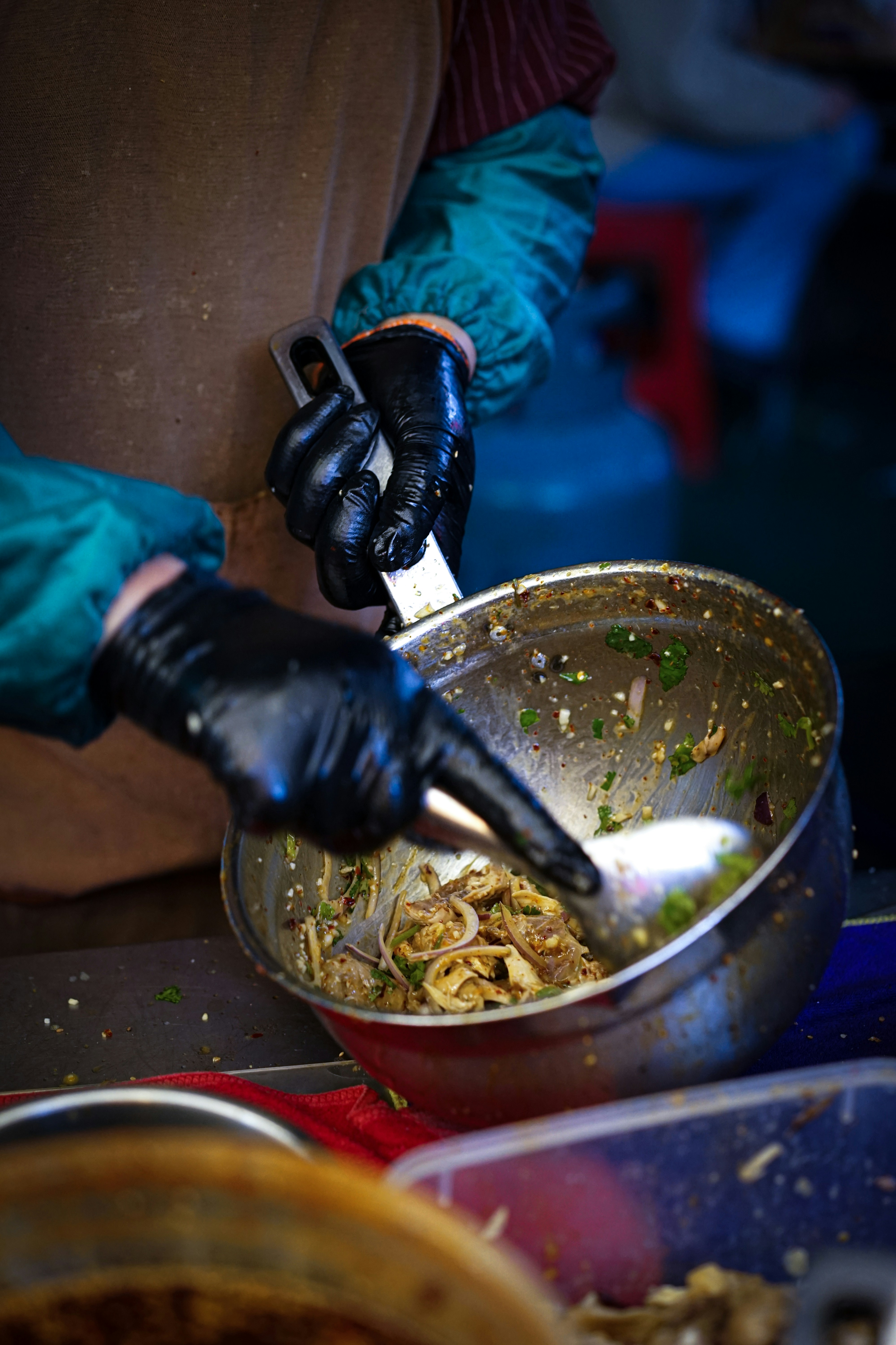 A person in gloves and gloves stirring food in a bowl