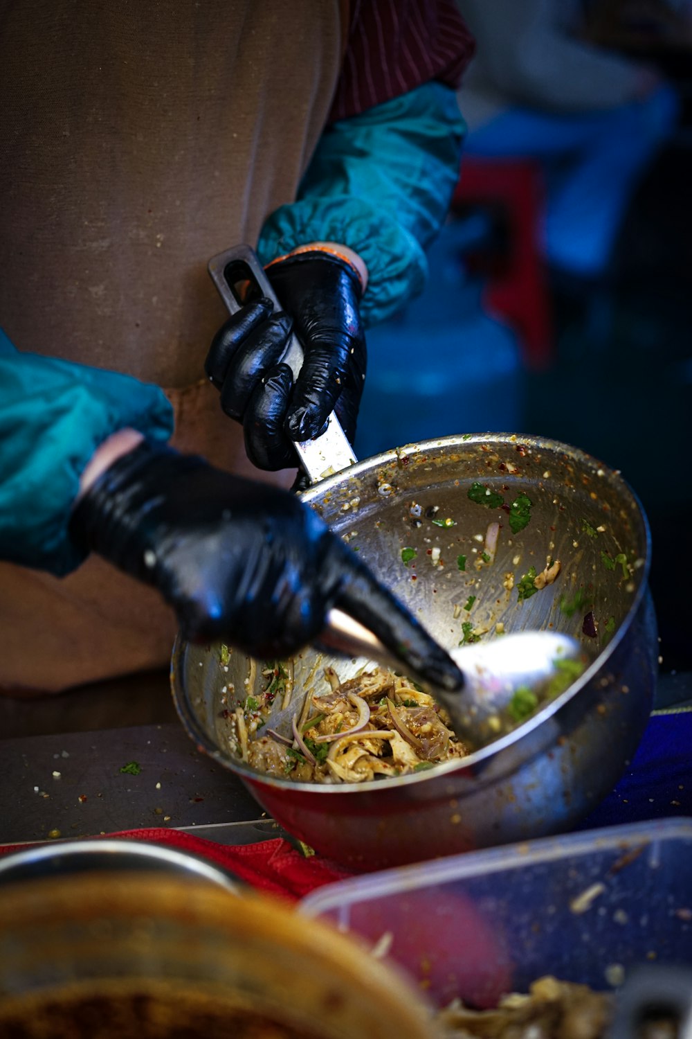 a person in gloves and gloves stirring food in a bowl