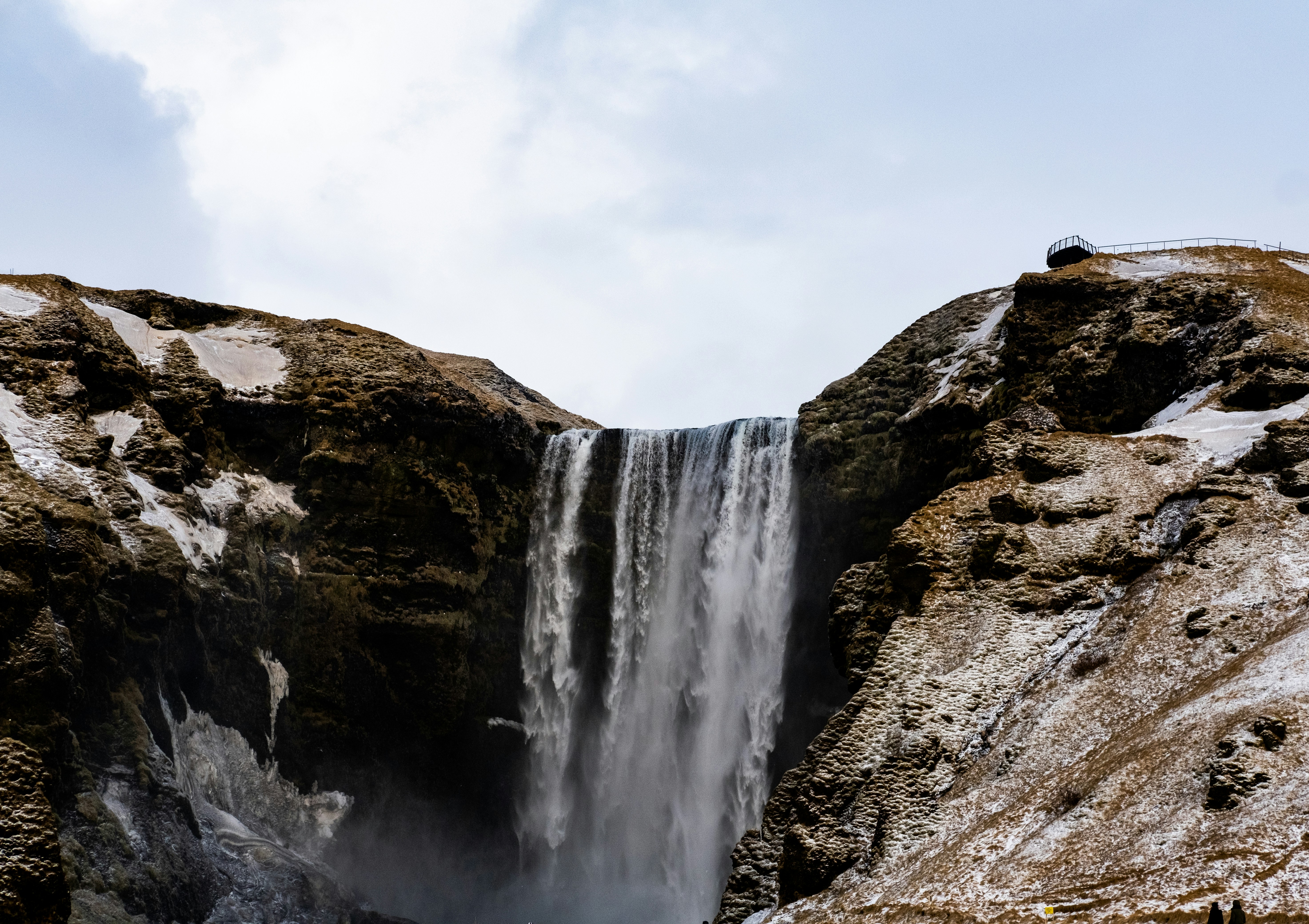 a large waterfall with snow on the ground, 