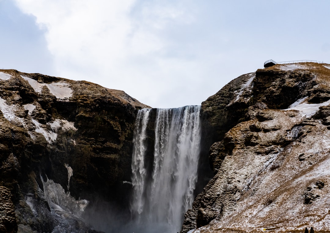 a large waterfall with snow on the ground,