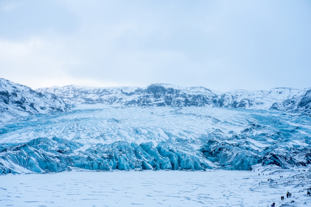 a large glacier surrounded by snow covered mountains