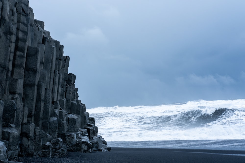 a black sand beach with waves crashing against the rocks