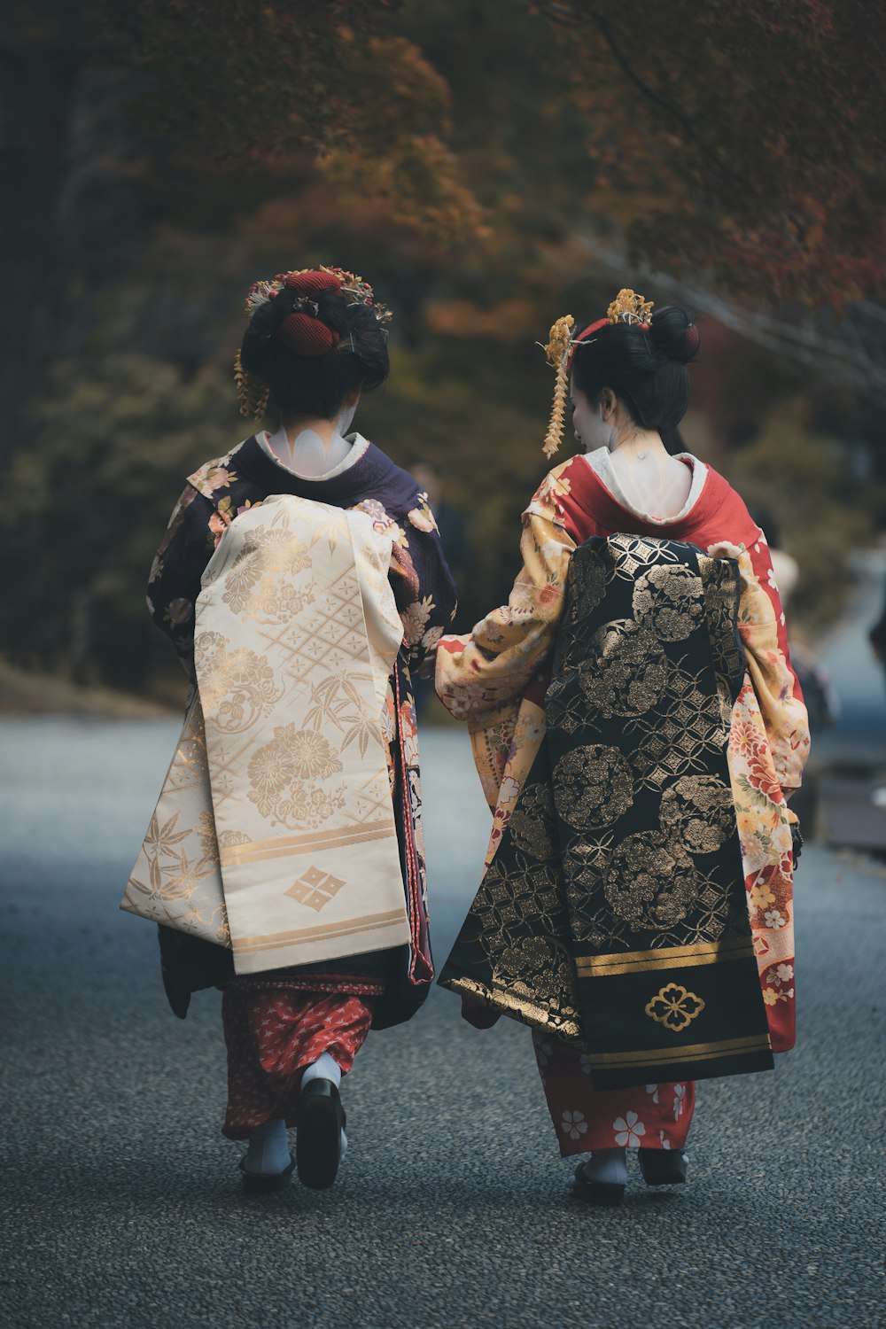 two geisha walking down a street holding hands