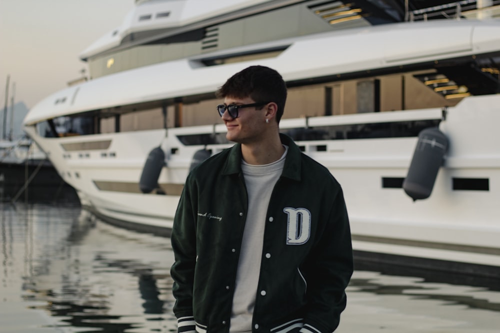 a man wearing sunglasses standing in front of a boat