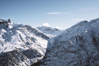 a mountain range covered in snow under a blue sky