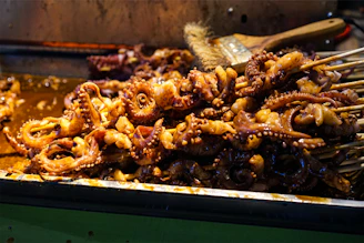 Close-up of tender octopus tentacles grilled over volcanic heat, glistening with a light glaze.