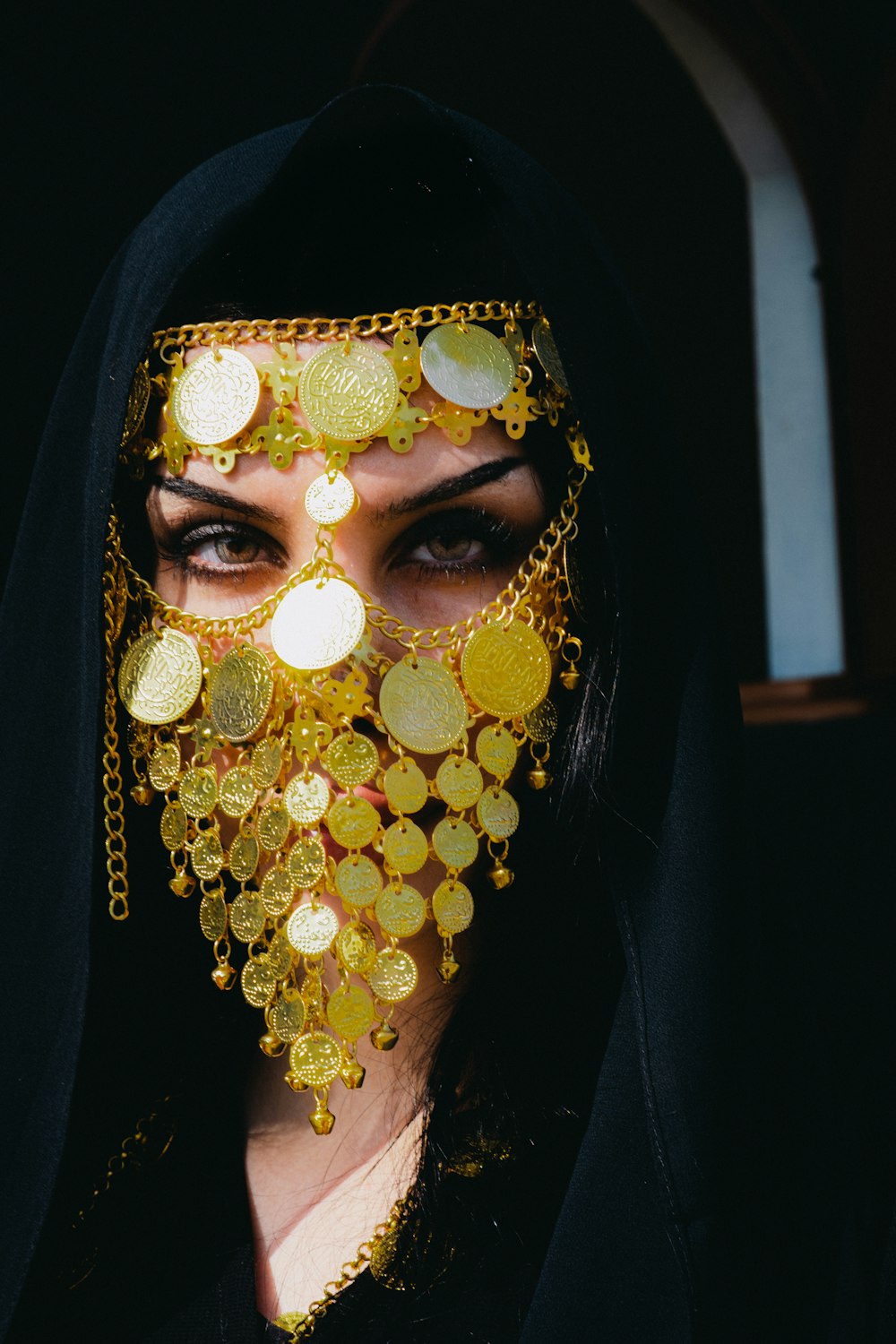 a woman in a black veil with gold coins on her face