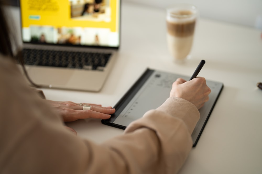 a woman is writing on a tablet with a pen