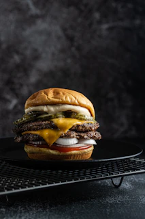 a cheeseburger on a black plate on a cooling rack