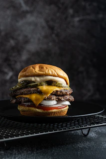 a cheeseburger on a black plate on a cooling rack