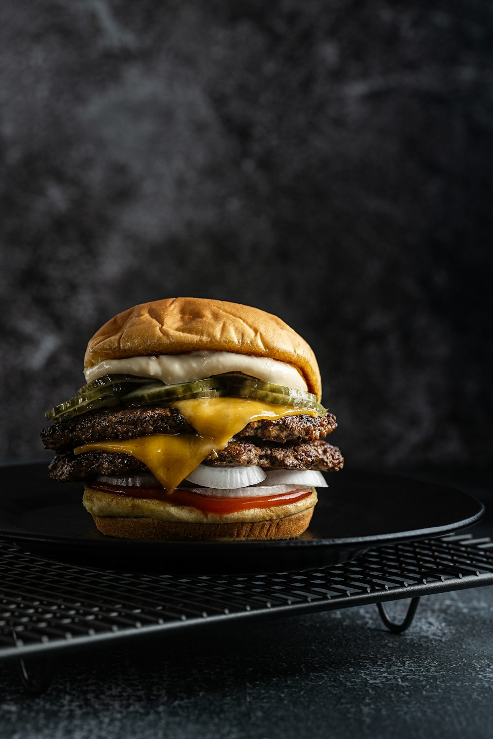 a cheeseburger on a black plate on a cooling rack