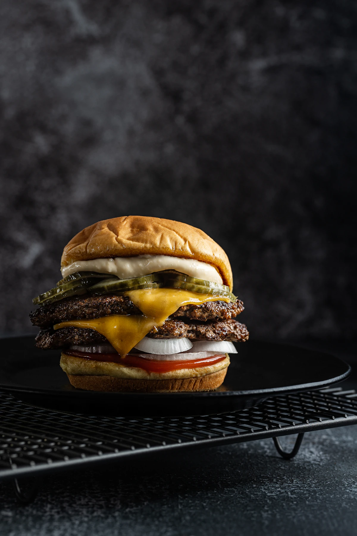 Hamburguesa con queso fotografiada sobre un plato oscuro