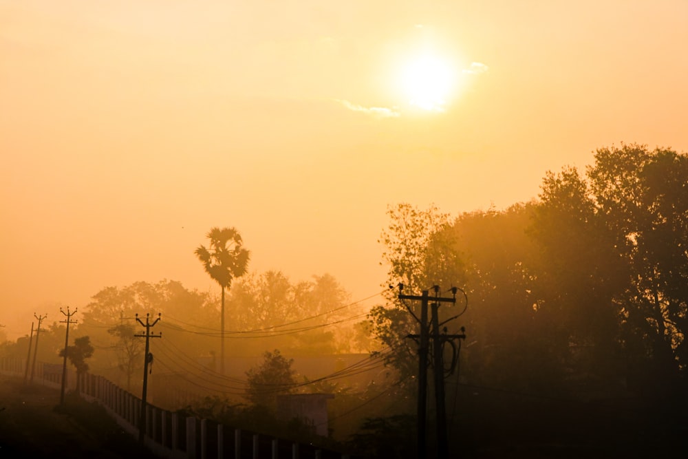 the sun is setting over the trees and hills