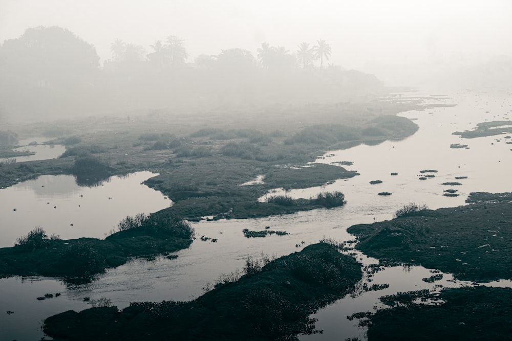 a foggy landscape with a river in the foreground