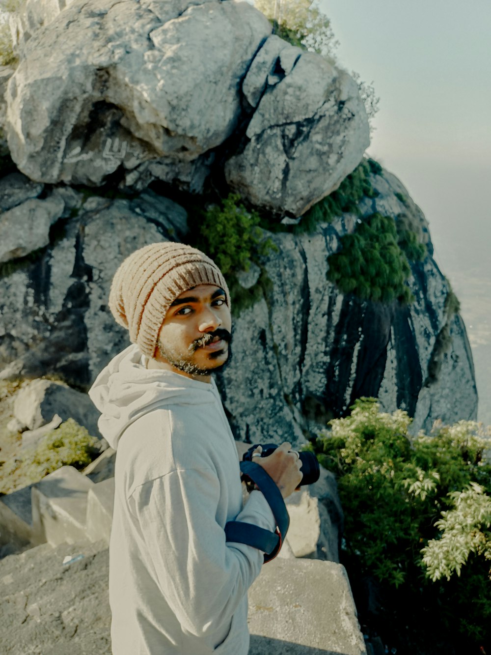a man with a beard and a beanie standing on a mountain