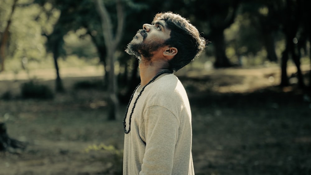 a man standing in a forest looking up at the sky