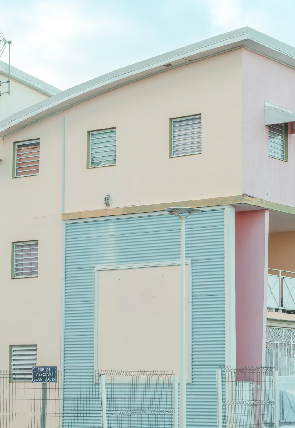 a pink and blue building next to a fence