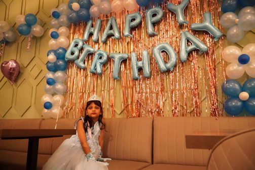 A princess in a shimmering gown waving to children at a birthday party.