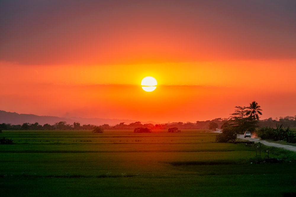 the sun is setting over a green field